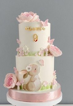 a three tiered cake decorated with pink flowers and an animal on the bottom layer