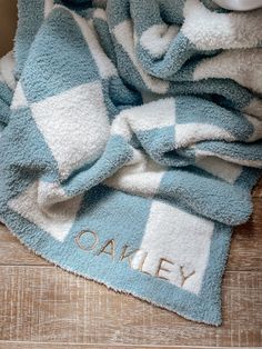 a blue and white checkered towel with the word oaky on it sitting on top of a wooden floor