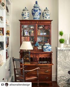 an old china cabinet with blue and white vases on it's top shelf