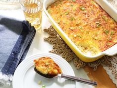 a casserole dish on a plate next to a glass of wine and napkin