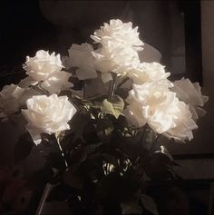 a vase filled with white flowers sitting on top of a table next to a mirror