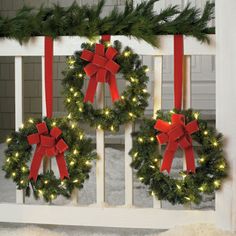 two christmas wreaths with red bows and lights