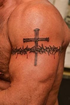 a man with a cross and barbed wire tattoo on his chest is looking at the camera