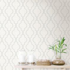 a table topped with plates and vases next to a wallpaper covered in white circles