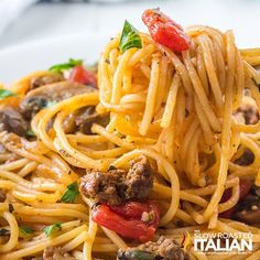 a fork full of spaghetti with meat and vegetables on it, ready to be eaten