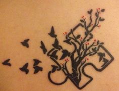 a tree with birds flying around it on the back of a woman's shoulder