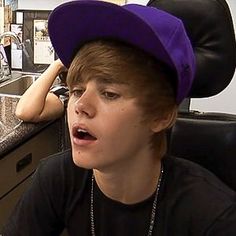 a boy wearing a purple hat sitting at a counter