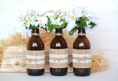 three brown bottles with white flowers in them