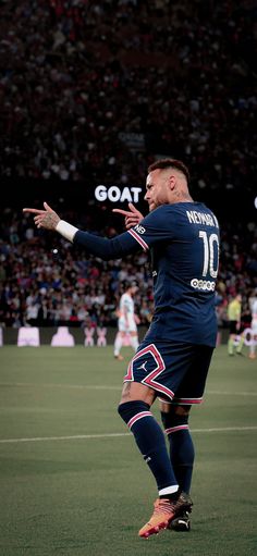 a soccer player is on the field with his arms out and hands in the air