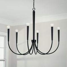 a black chandelier hanging from the ceiling in a room with white walls and windows