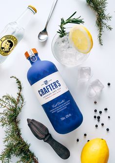 a bottle of crafters gin next to lemons, ice and peppercorst