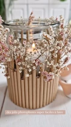 a vase filled with lots of flowers on top of a white wooden table next to a candle