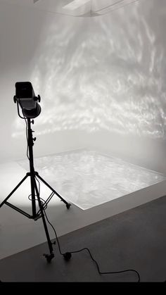 an empty room with a camera on a tripod in front of a white backdrop