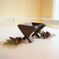 a wooden sculpture sitting on top of a white table next to flowers and greenery