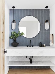 a white sink sitting under a round mirror