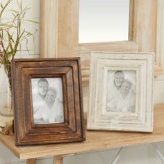 two frames sitting on top of a wooden table next to a vase filled with flowers