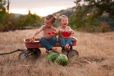 two children sitting in a wagon with watermelon