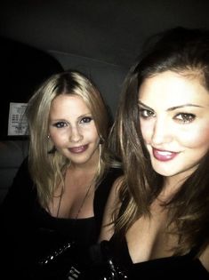 two beautiful women sitting next to each other in the back seat of a car at night