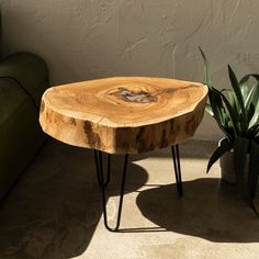 a wooden table sitting next to a green couch and potted plant on the floor