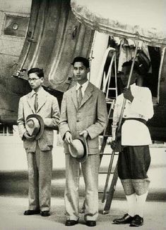 three men standing next to each other in front of an airplane