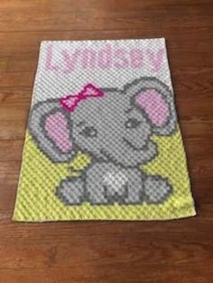 an elephant with a pink bow on it's head sitting on a wooden floor