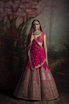 a woman in a pink and gold lehenga