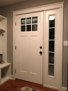 a white front door with two glass panes on the side and shelves below it