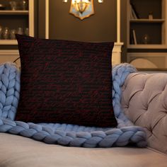 a black and red pillow sitting on top of a couch next to a blue blanket