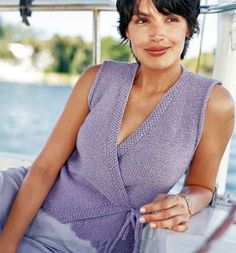 a woman sitting on top of a boat wearing a purple dress