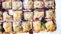 blueberry crumbled pastries are arranged on a cutting board with fresh berries