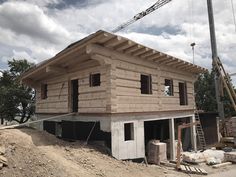 a house being built on the side of a dirt hill with a crane in the background