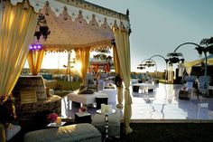 an outdoor wedding venue set up with white and yellow drapes, couches and tables