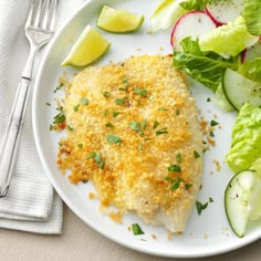 a white plate topped with chicken and salad next to a fork, knife and napkin