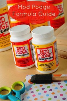 several bottles of mod podge paint sitting on a table next to scissors and glue