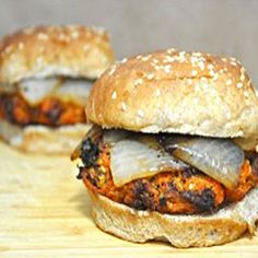 two burgers sitting on top of a wooden cutting board