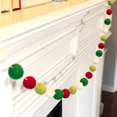 the garland is decorated with pom - poms and red, green, yellow, and white balls