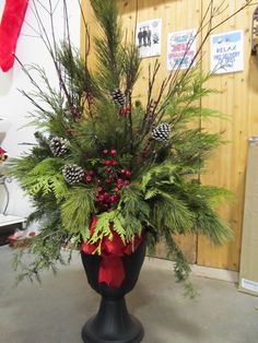 a vase filled with greenery and pine cones