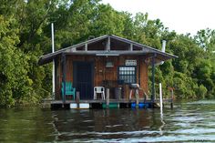 a small house sitting on top of a body of water next to a lush green forest