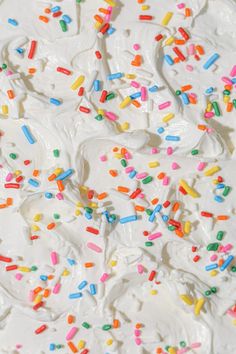 white frosted cake with sprinkles and multicolored icing on top