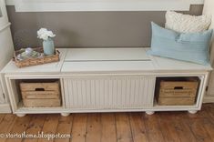 a white bench with two baskets on it and a blue pillow sitting on top of it