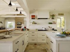 a kitchen filled with lots of white cabinets and counter top space next to a window