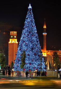 a large blue christmas tree sitting in the middle of a street