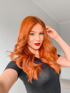 a woman with long red hair is posing for the camera and has her hands on her head