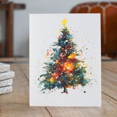 a card with a christmas tree painted on the front and bottom, sitting on a table