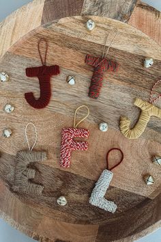 several knitted ornaments are arranged on a wooden board with beads and thread in the shape of letters