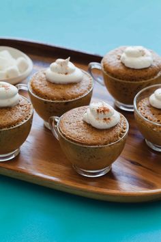 several desserts are arranged on a wooden tray