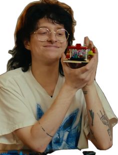 a man with glasses holding a small model house in front of his face while sitting at a table