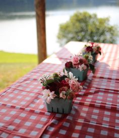 flowers are lined up on the table at an outdoor gathering by the water's edge