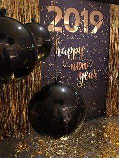 balloons and streamers in front of a new year's eve backdrop with gold confetti