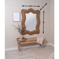 a wooden bench sitting under a mirror next to a vase with flowers on top of it